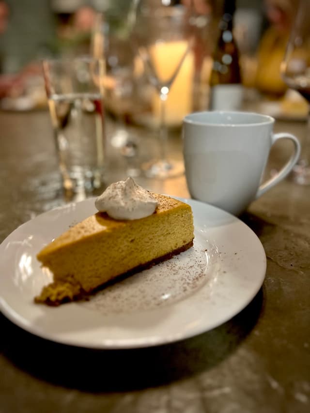 A slice of pie with spices, cream, and coffee.